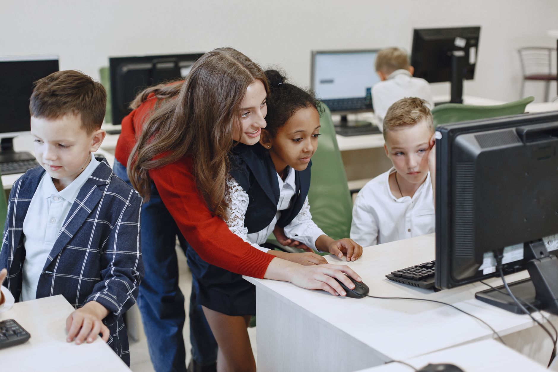 Aula de informática, com um professor a acompanhar o trabalho nos computadores
